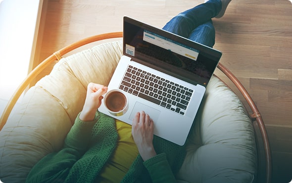 Người dùng laptop và cầm ly cà phê khi ngồi thư giãn trên ghế