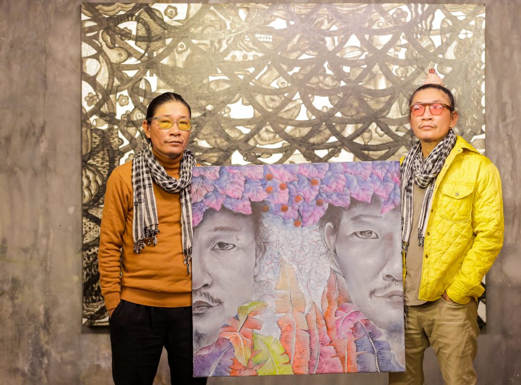 Hai người đàn ông đứng trước bức tranh chân dung nghệ thuật trừu tượng đầy màu sắc