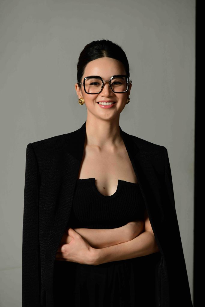 Ch&acirc;n dung người phụ nữ mặc &aacute;o blazer đen v&agrave; đeo k&iacute;nh gọng vu&ocirc;ng đang mỉm cười