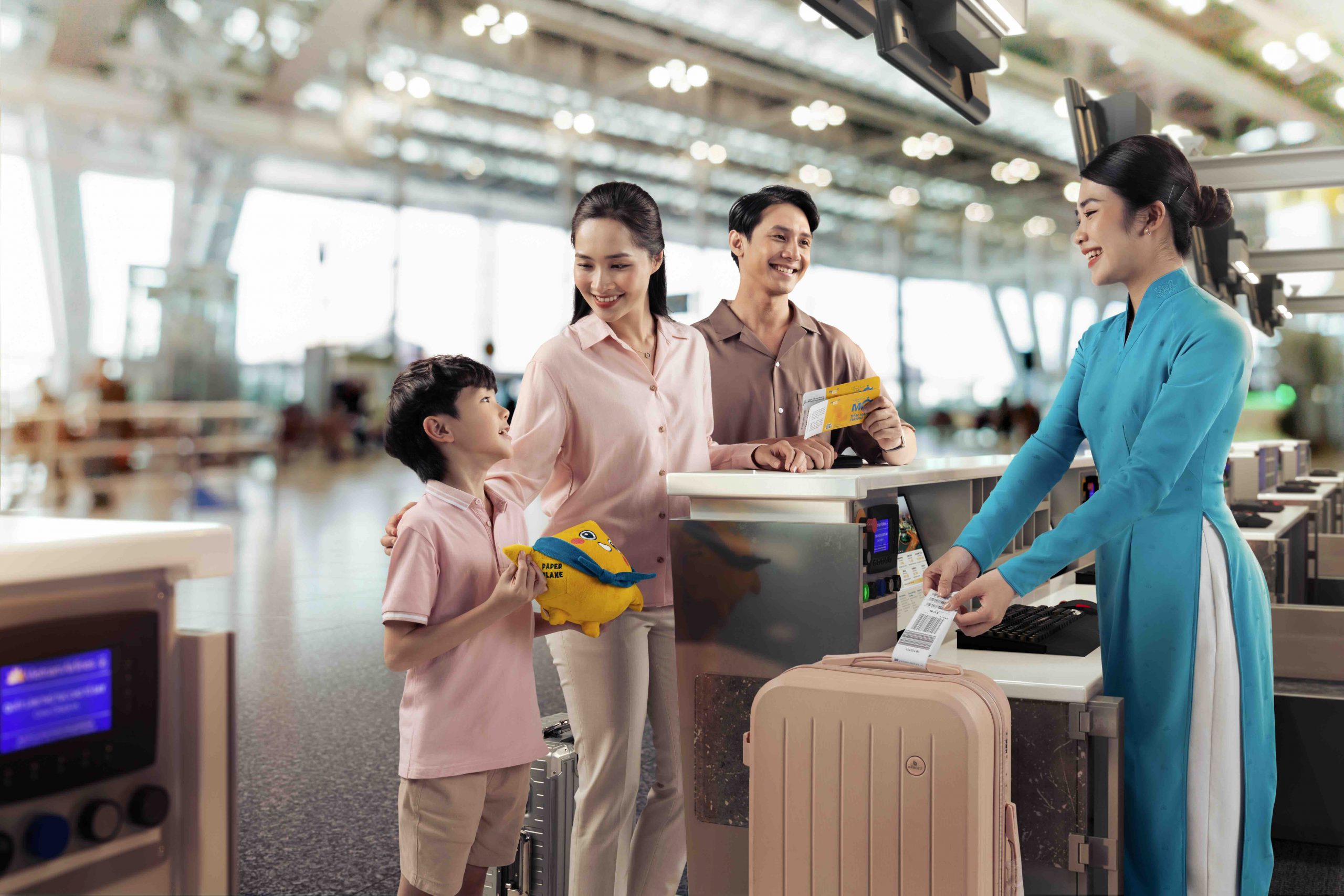 Gia đình trẻ vui vẻ làm thủ tục check-in tại quầy Vietnam Airlines ở sân bay