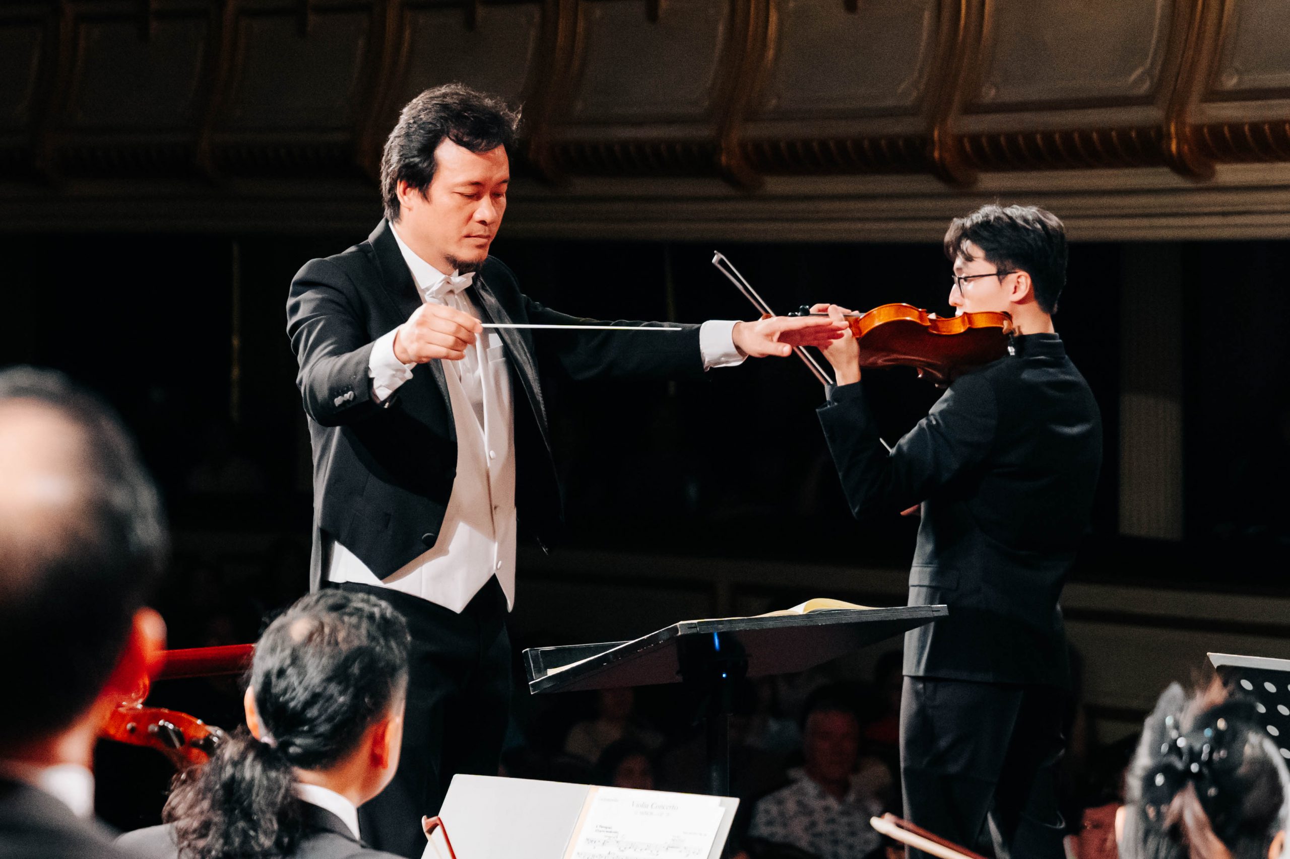 Nhạc trưởng điều khiển nghệ sĩ violin biểu diễn trong buổi hòa nhạc cổ điển